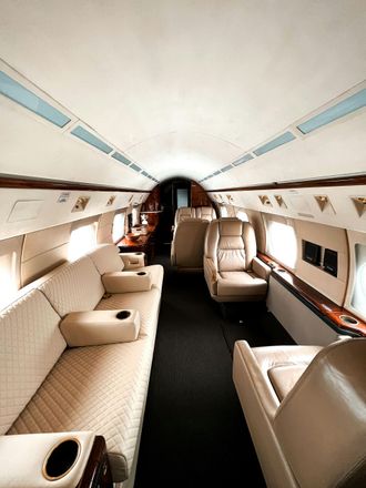 The inside of a private jet with a couch and chairs