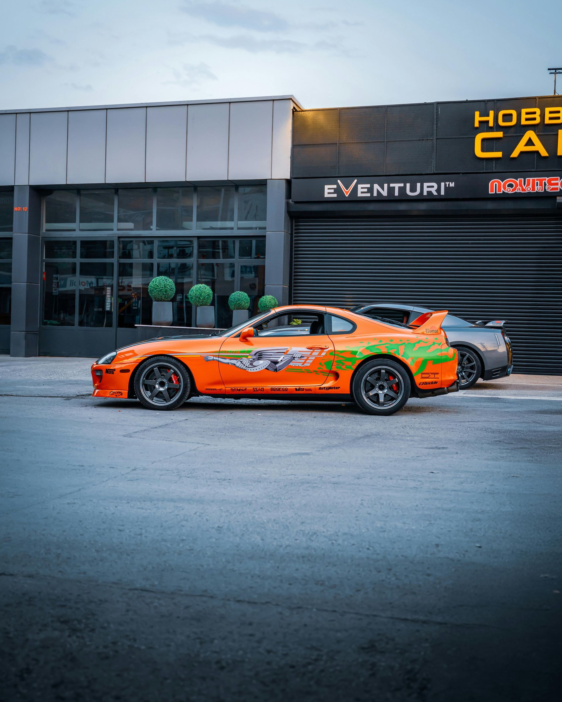 An orange car is parked in front of a building.