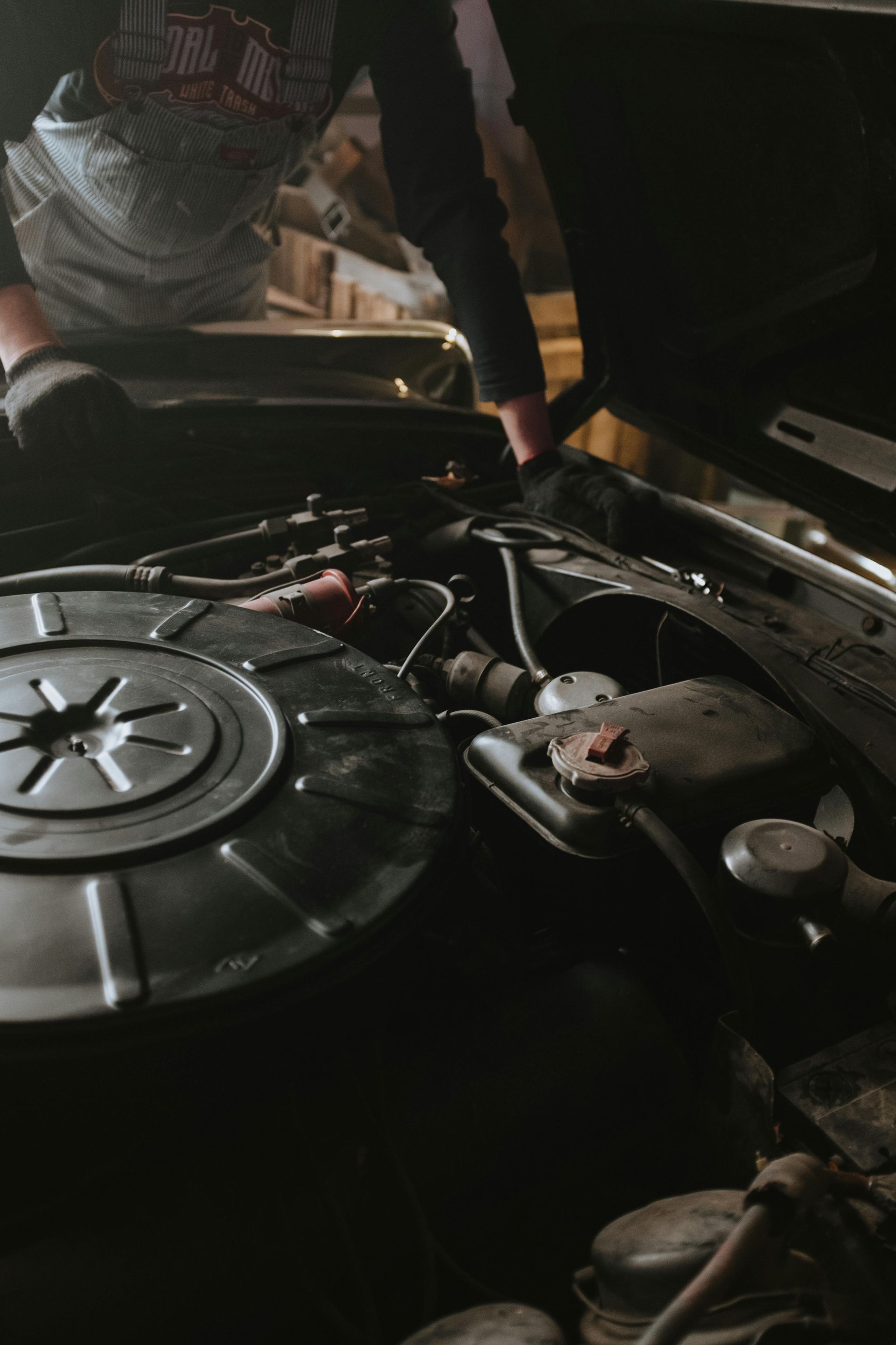 A man is working on the engine of a car with the hood open.