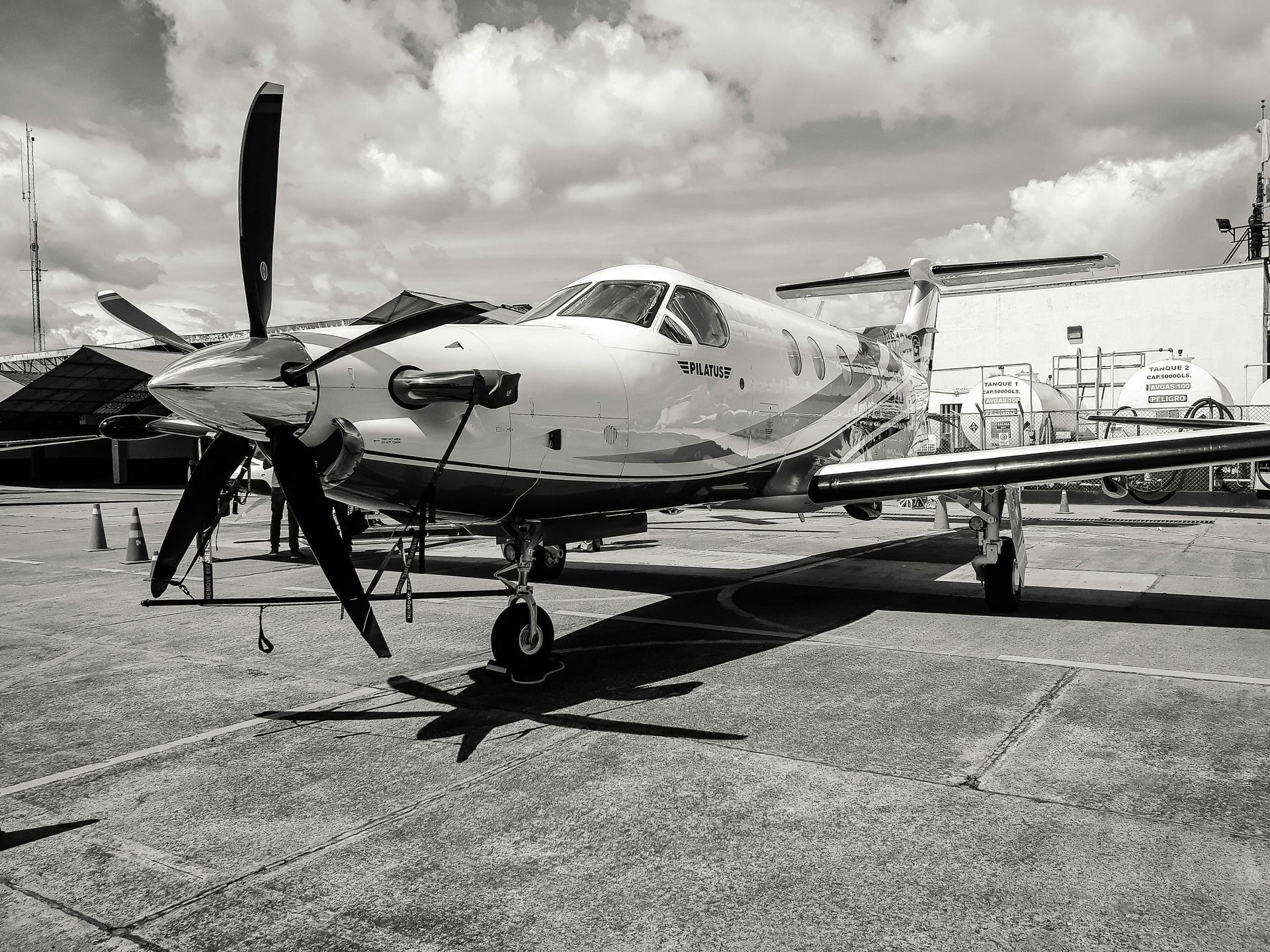 A small propeller plane is parked on the tarmac in a black and white photo.