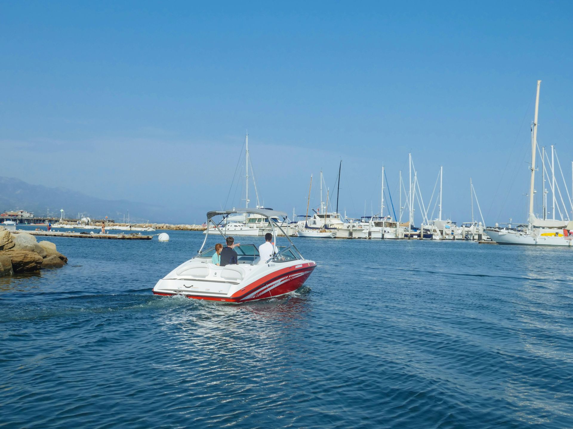 A red and white boat is floating on top of a body of water.