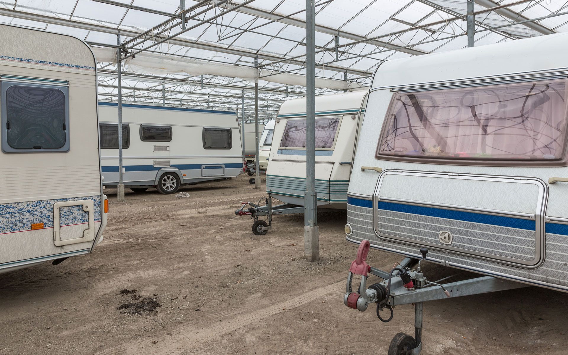 A row of caravans are parked in a greenhouse.