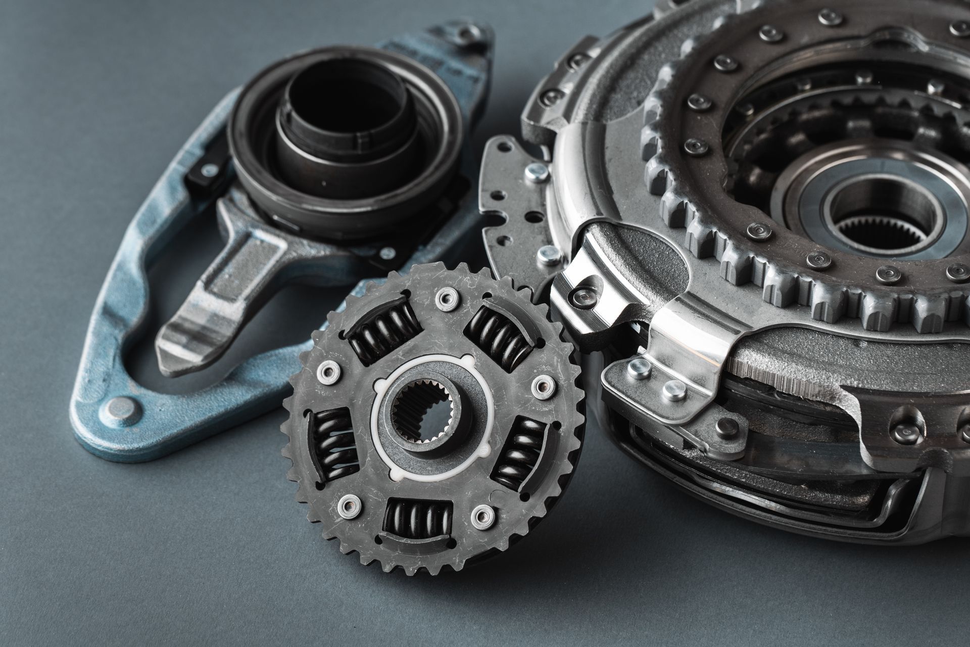 Three automotive clutch components, including a release bearing and friction plate, arranged on a dark gray background.