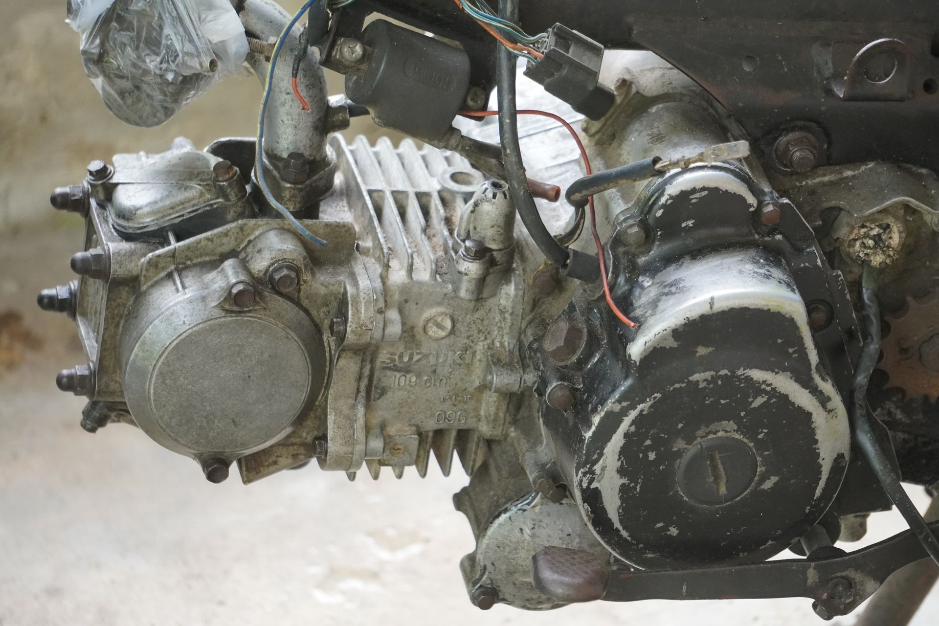 Dirty, used motorcycle engine with exposed cooling fins and a black side casing.