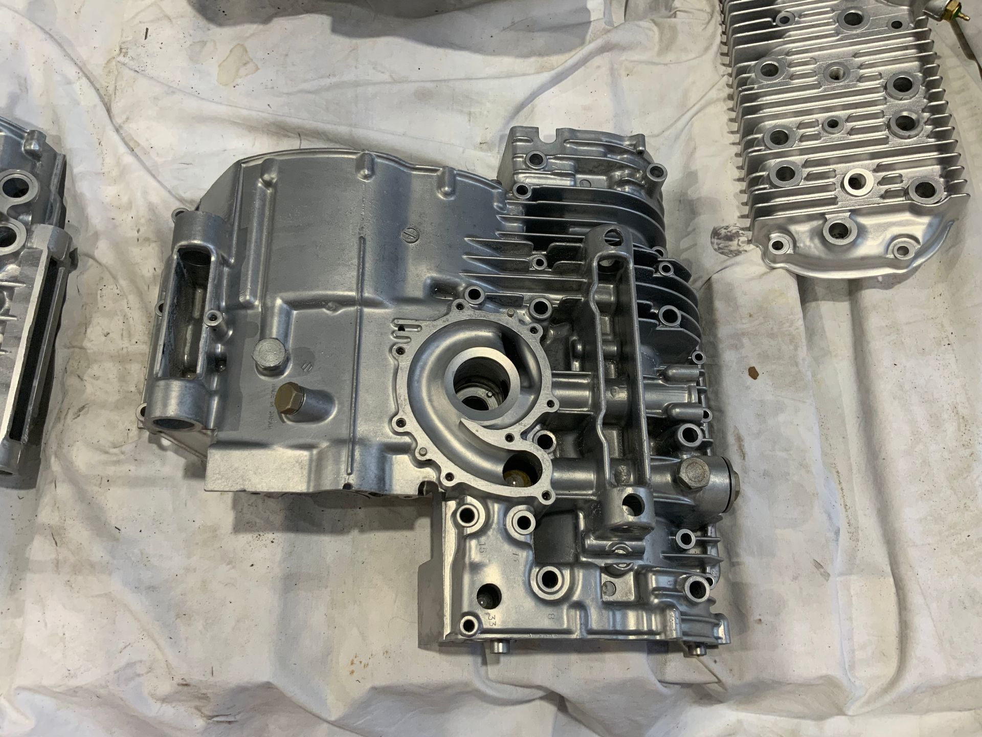 An overhead view of clean, disassembled silver engine components laid out on white protective paper.