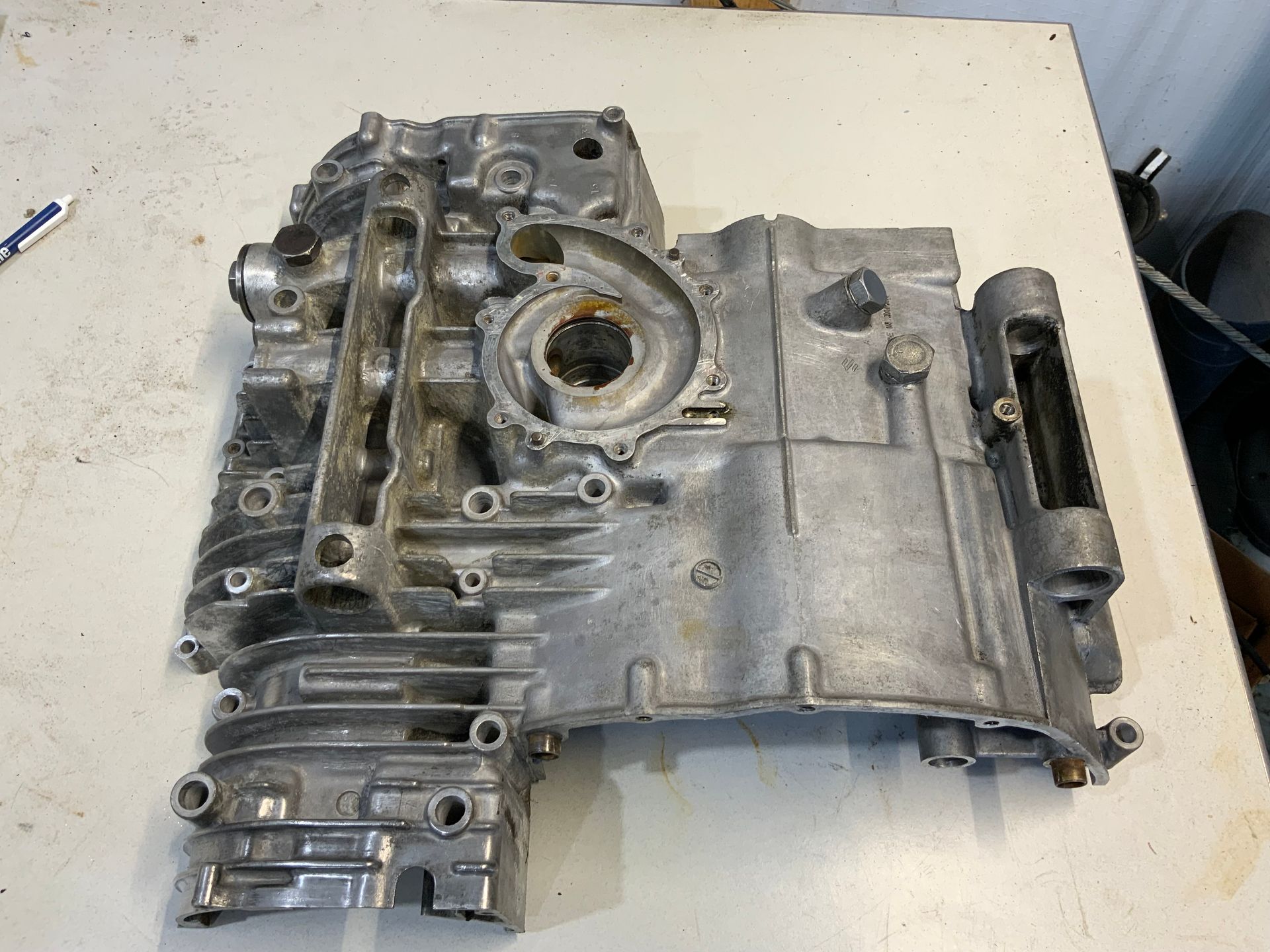 A silver, cast-aluminum engine crankcase half resting on a white table.