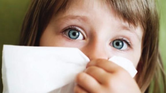 A little girl blowing her nose with a napkin