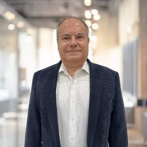 A smiling doctor in a lab coat with a stethoscope around his neck.