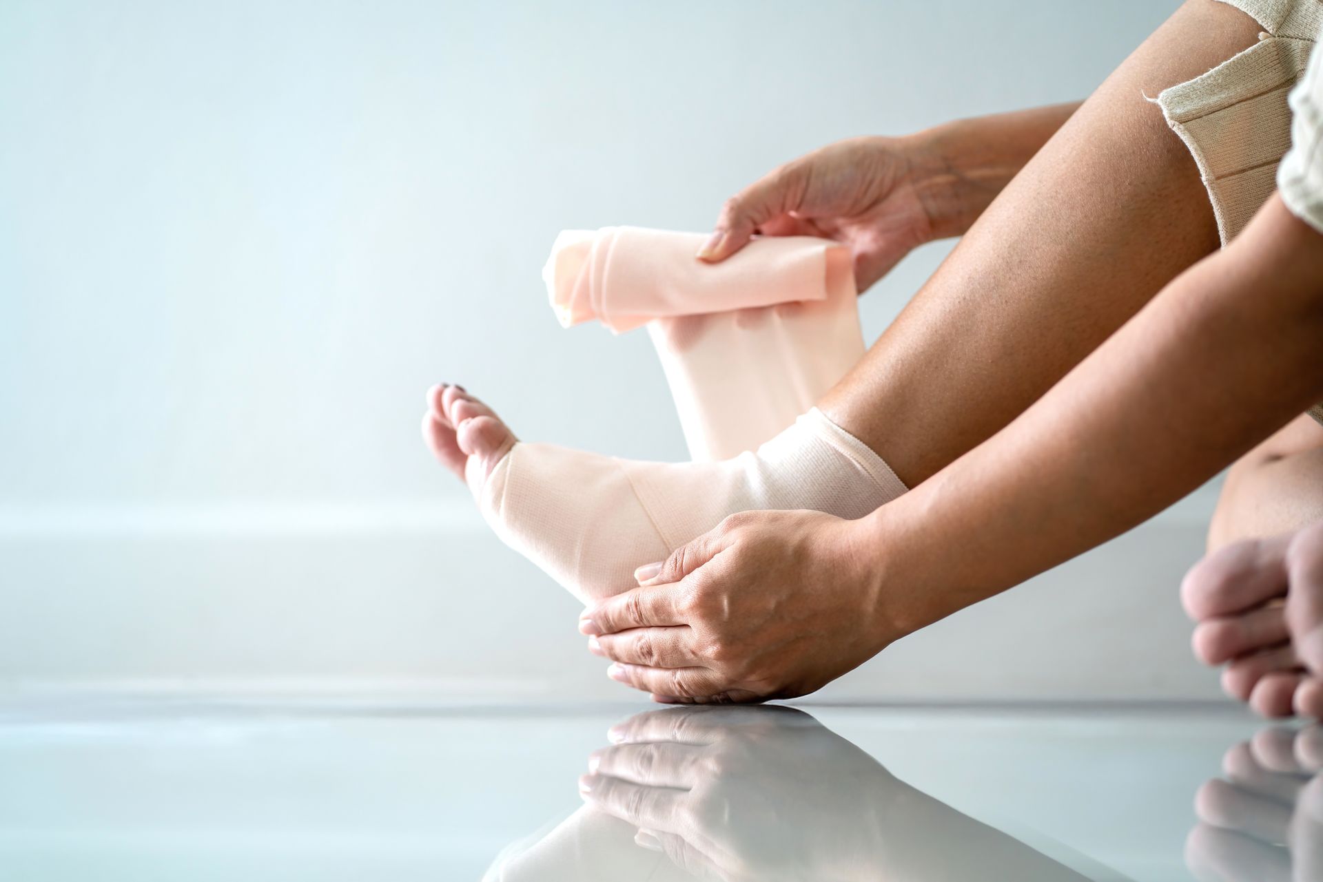Person wrapping an ankle with a bandage, indoors.
