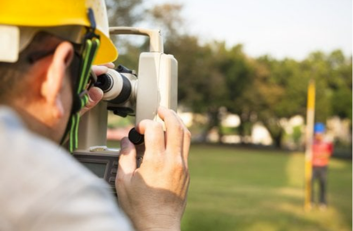 A man is using a theodolite to measure a field.