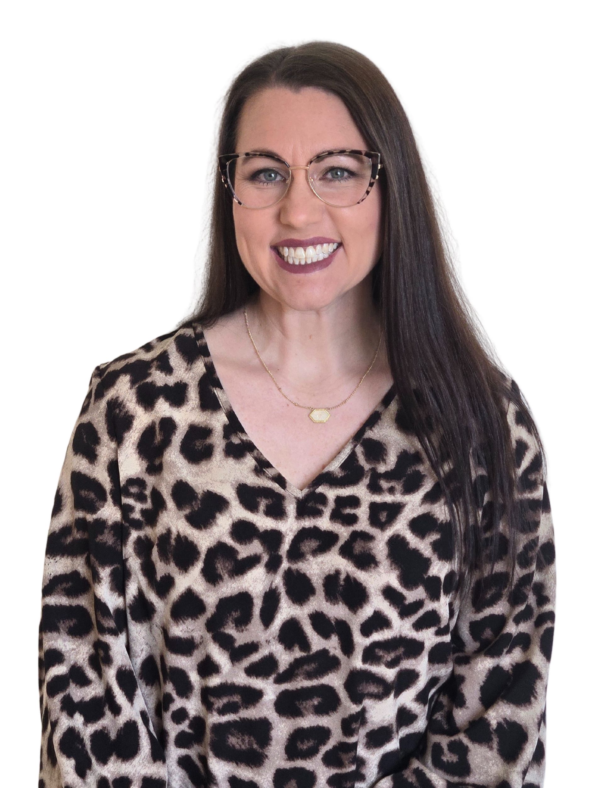 Woman with glasses smiles, wearing black leopard print shirt, against a white backdrop.