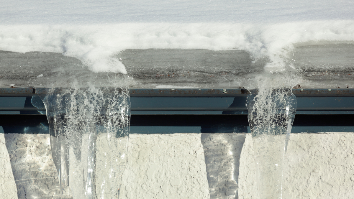 Icicles hanging from a roof with snow and ice.