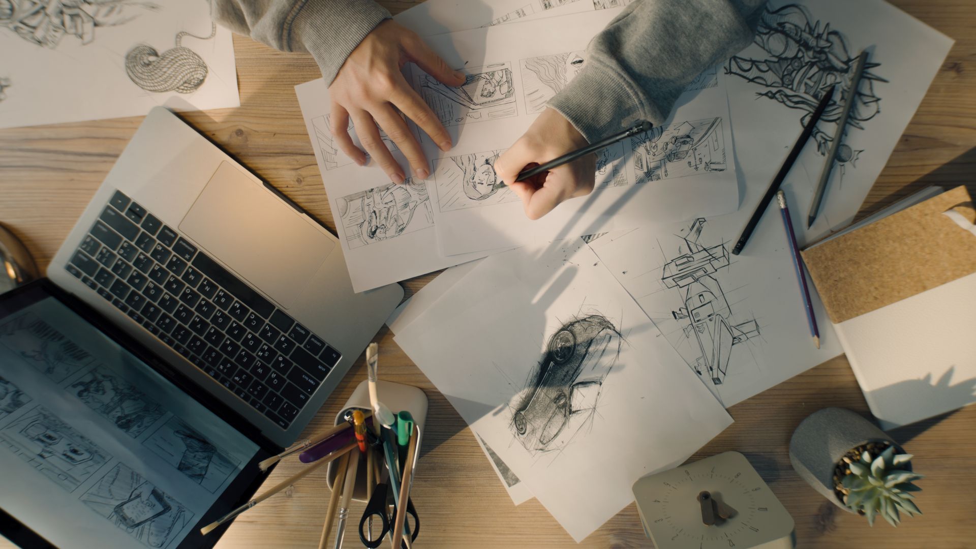 hands illustrating an image with a laptio open