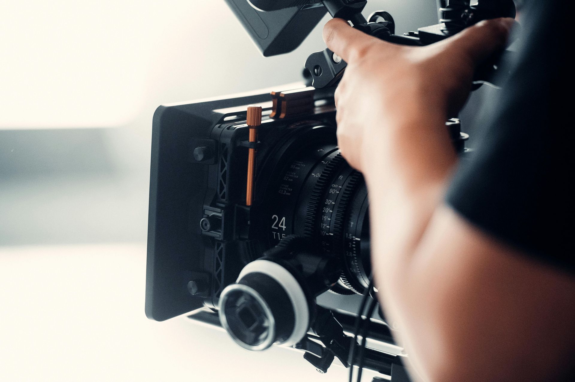 Person adjusting a professional video camera with attached monitor in a studio setting