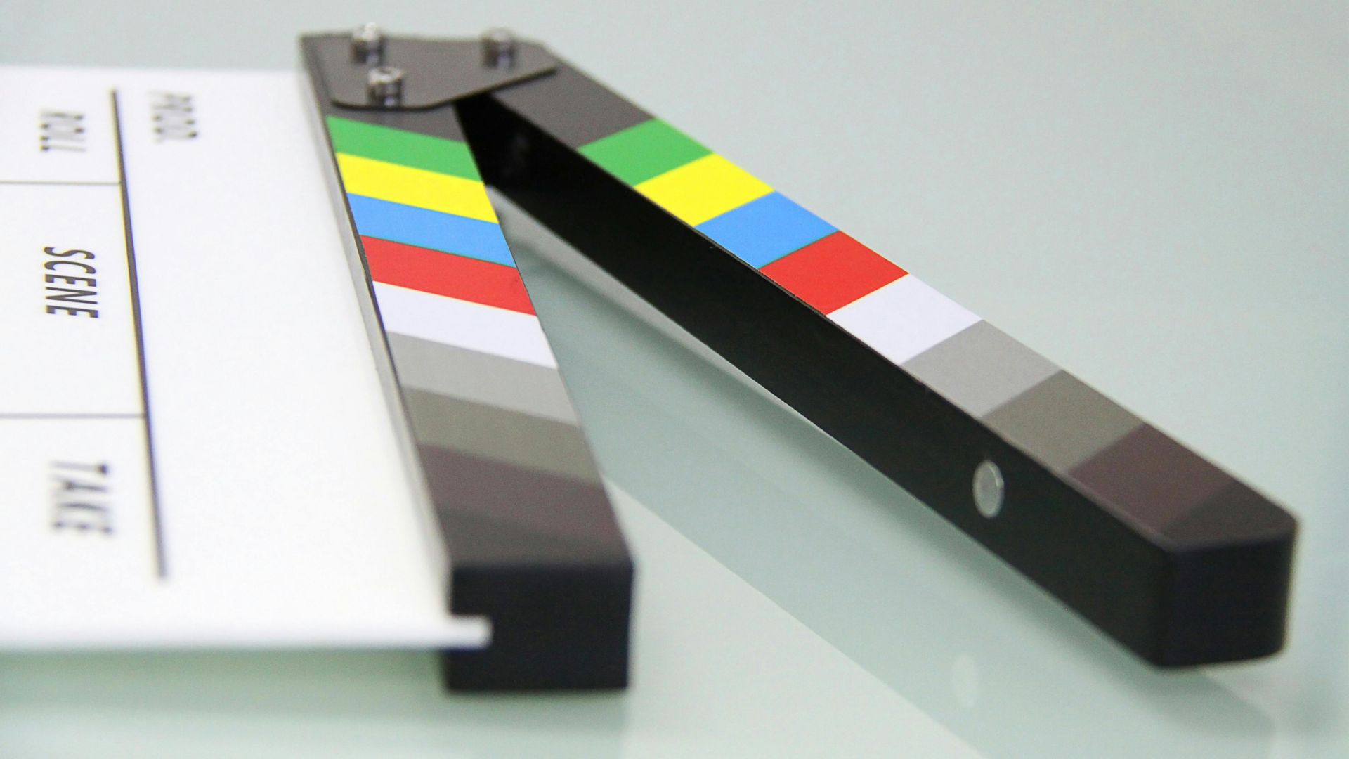 Clapperboard on a white surface, open, with color bars and text.