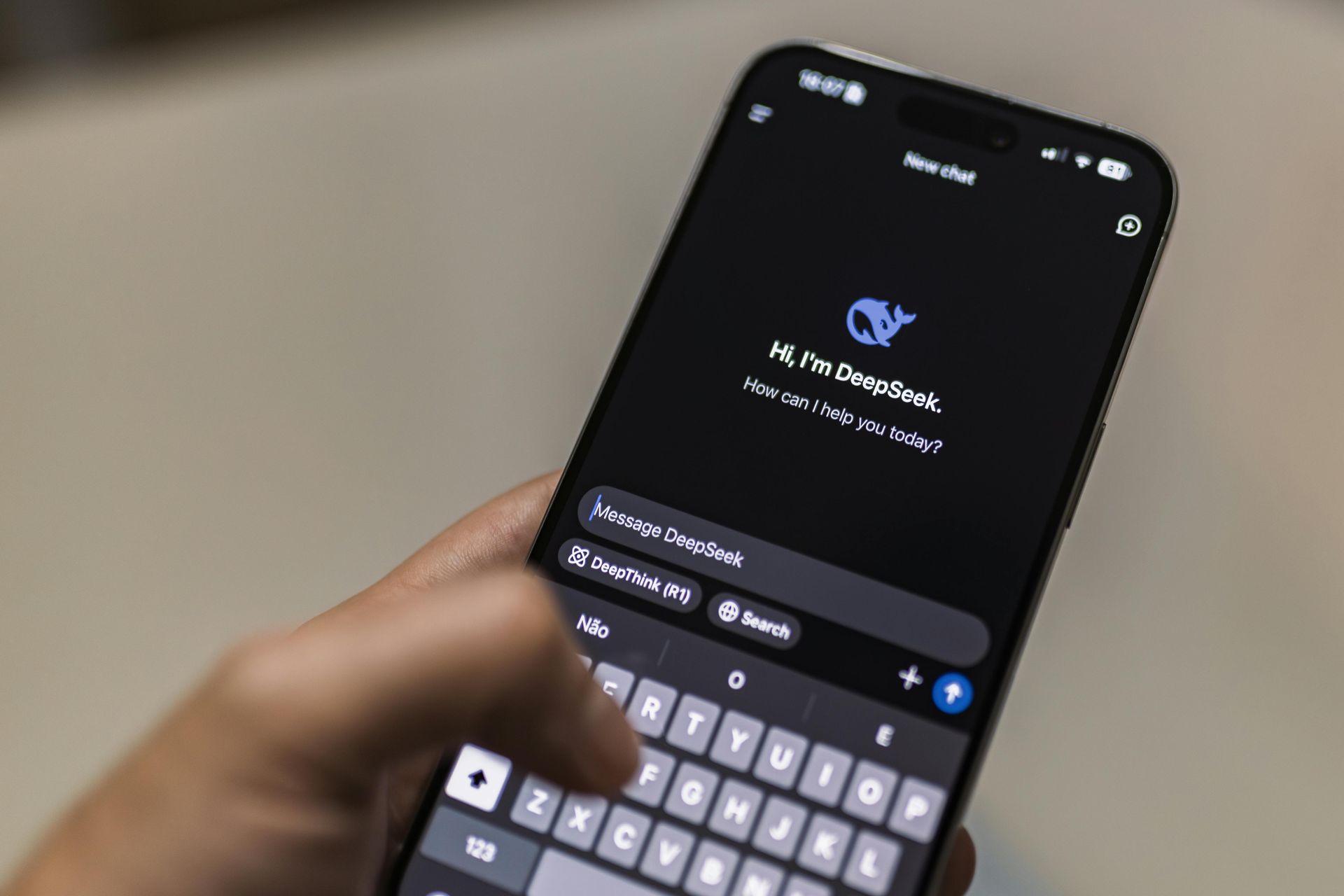 A close-up of a hand typing on a smartphone displaying the DeepSeek AI chat interface.