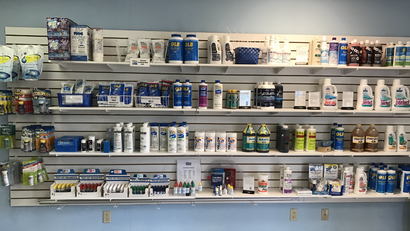 Wall of pharmacy shelves stocked with medical supplies and bottles in a store.