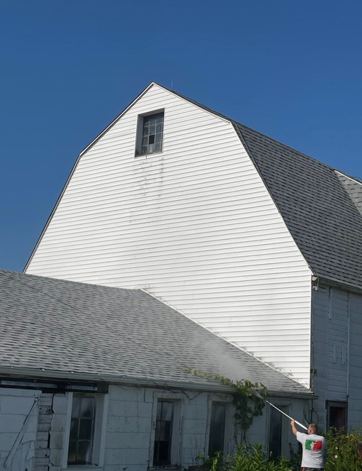 White barn with gray roof against a blue sky.
