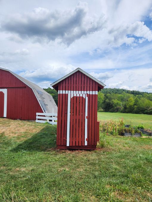White barn with red trim and a blue sky.