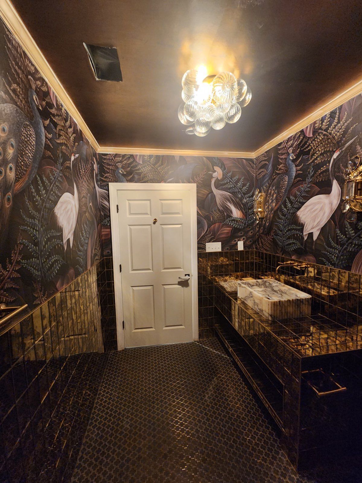 Colorful mural on a corrugated metal building with car and small white structure in front.