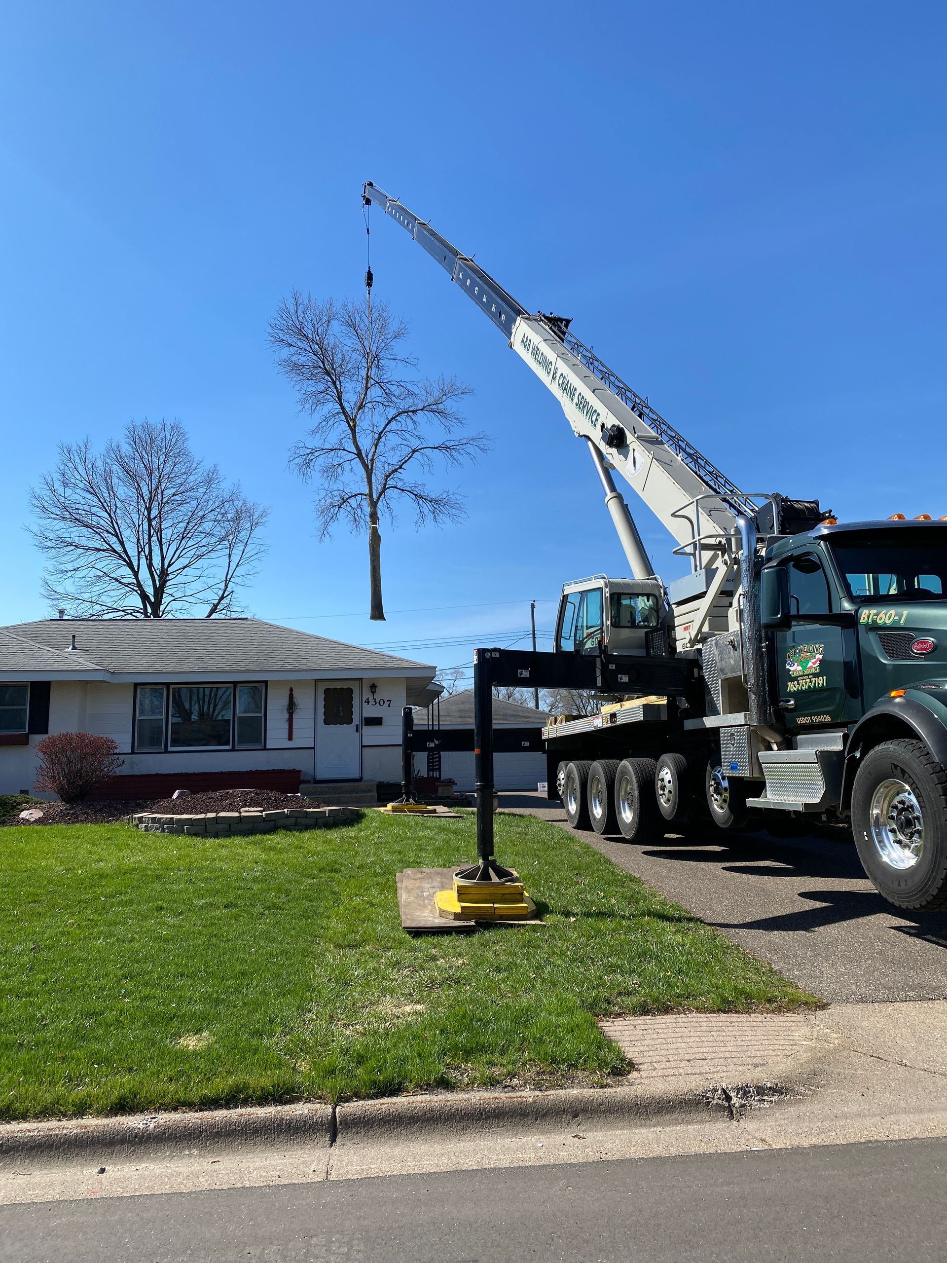 A Crane is Lifting a Tree in from the Back of the House  | Minneapolis, MN | Arbor Tree Service