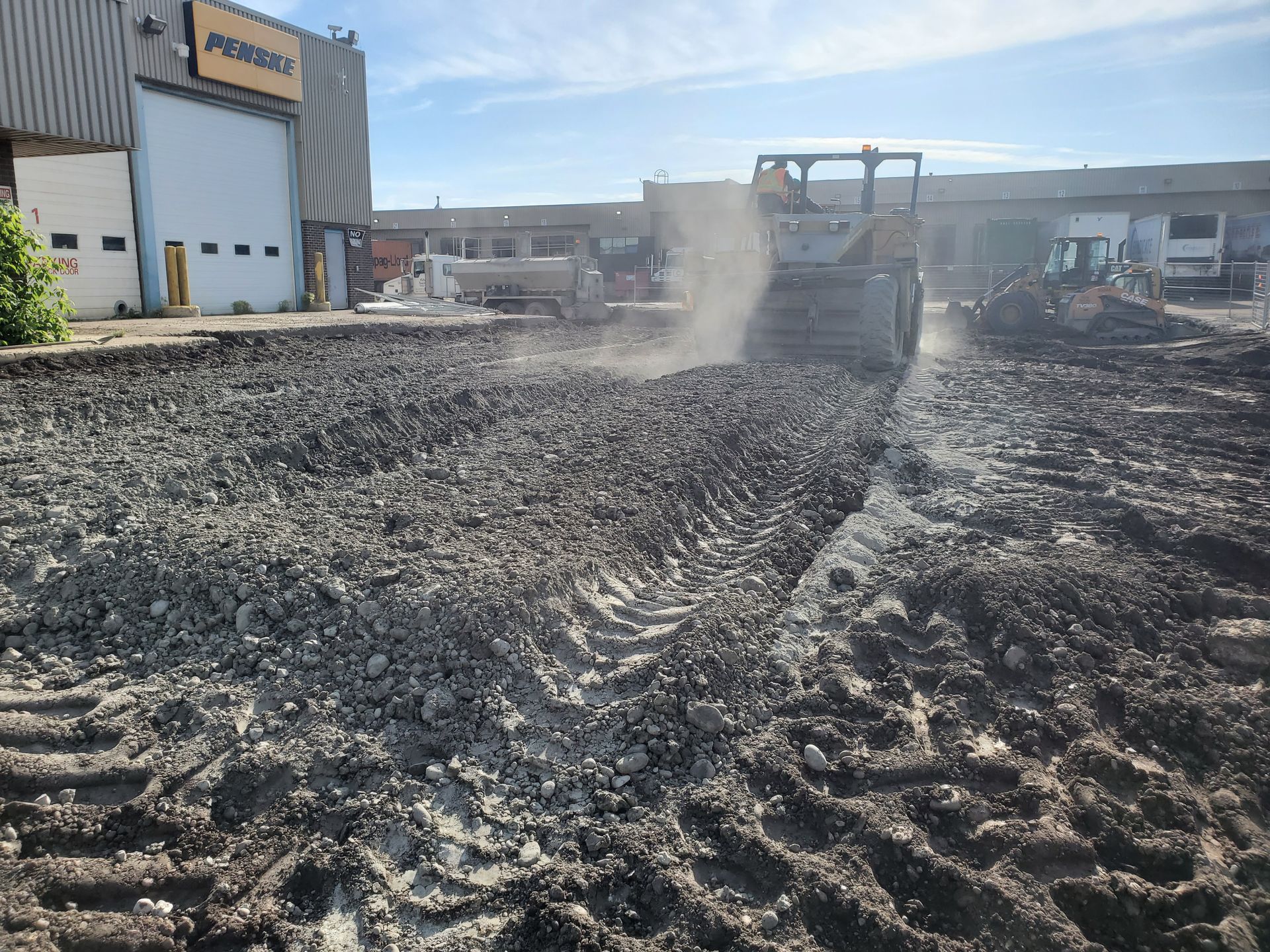 A bulldozer is working on a dirt field in front of a building.