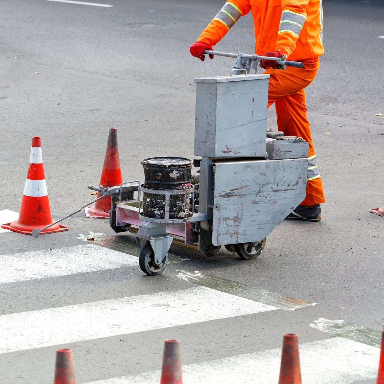 A man is using a machine to paint a crosswalk