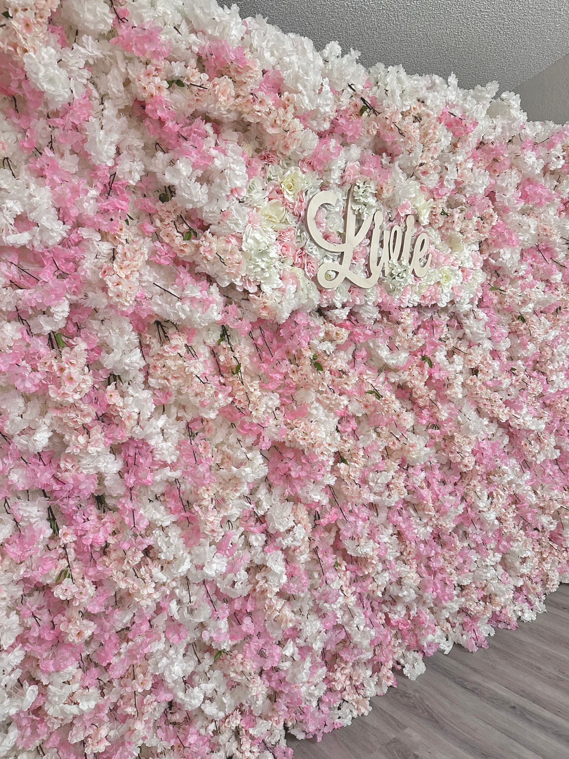 A wall of pink and white flowers is sitting on a table.