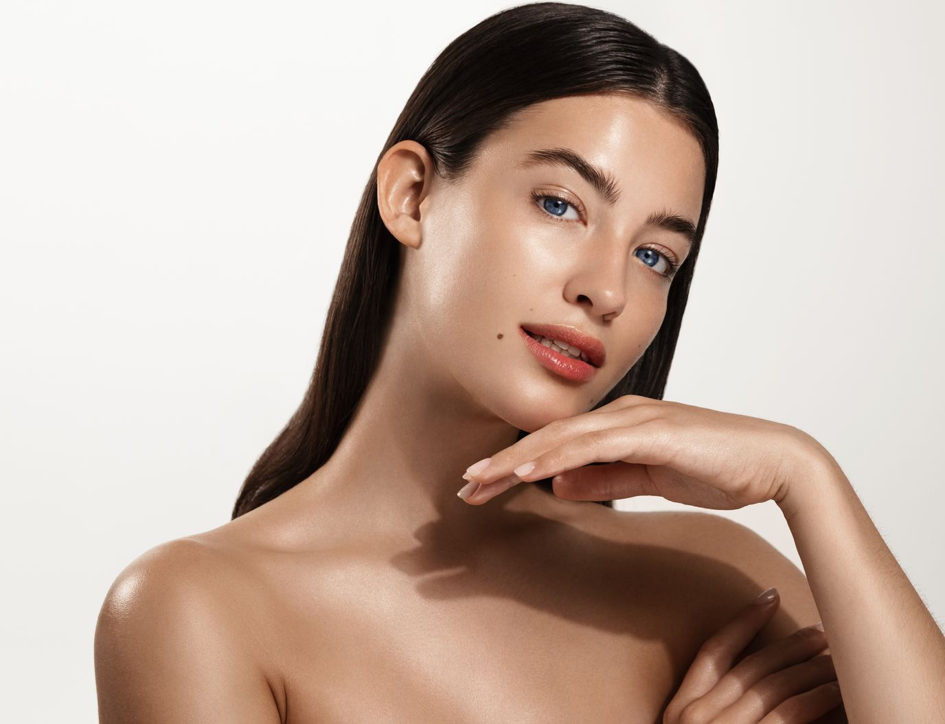 Woman with smooth skin, hand on chin, looking at camera.