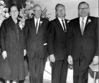 A group of men in suits and ties are standing next to each other in a black and white photo.