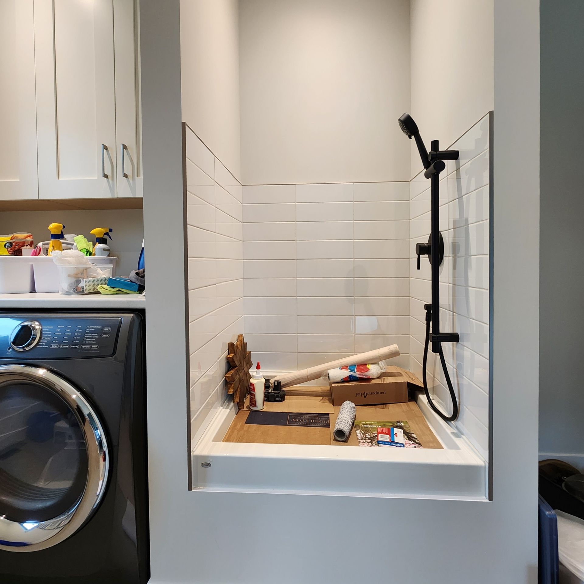 A laundry room with a washing machine and a shower