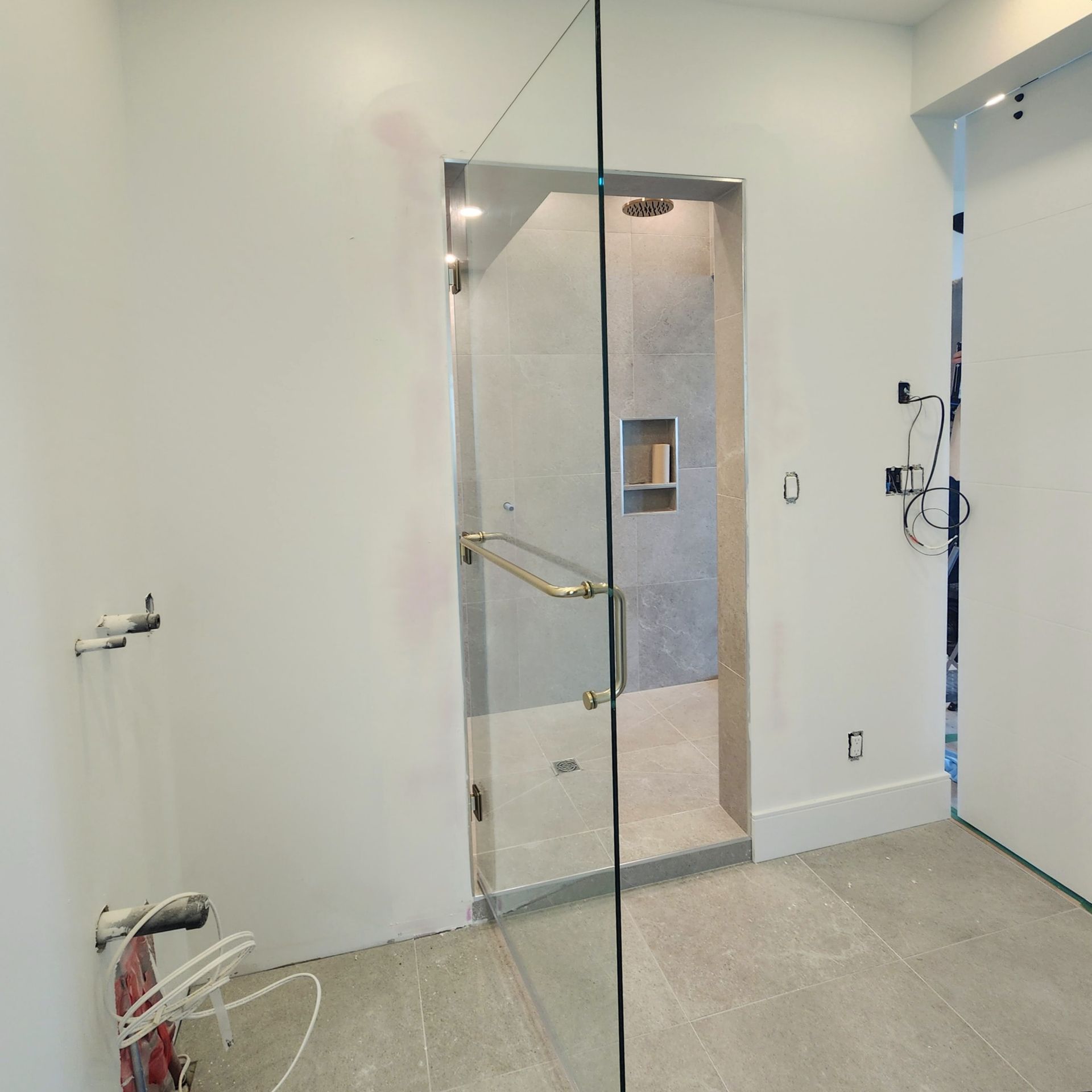 A bathroom with a walk in shower with a glass door