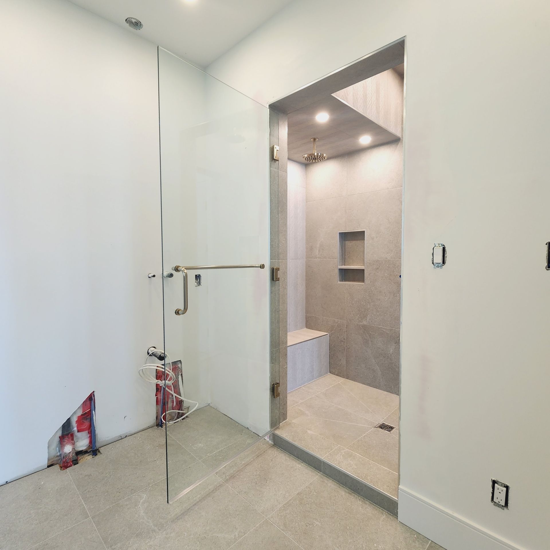 A bathroom with a walk in shower with a glass door