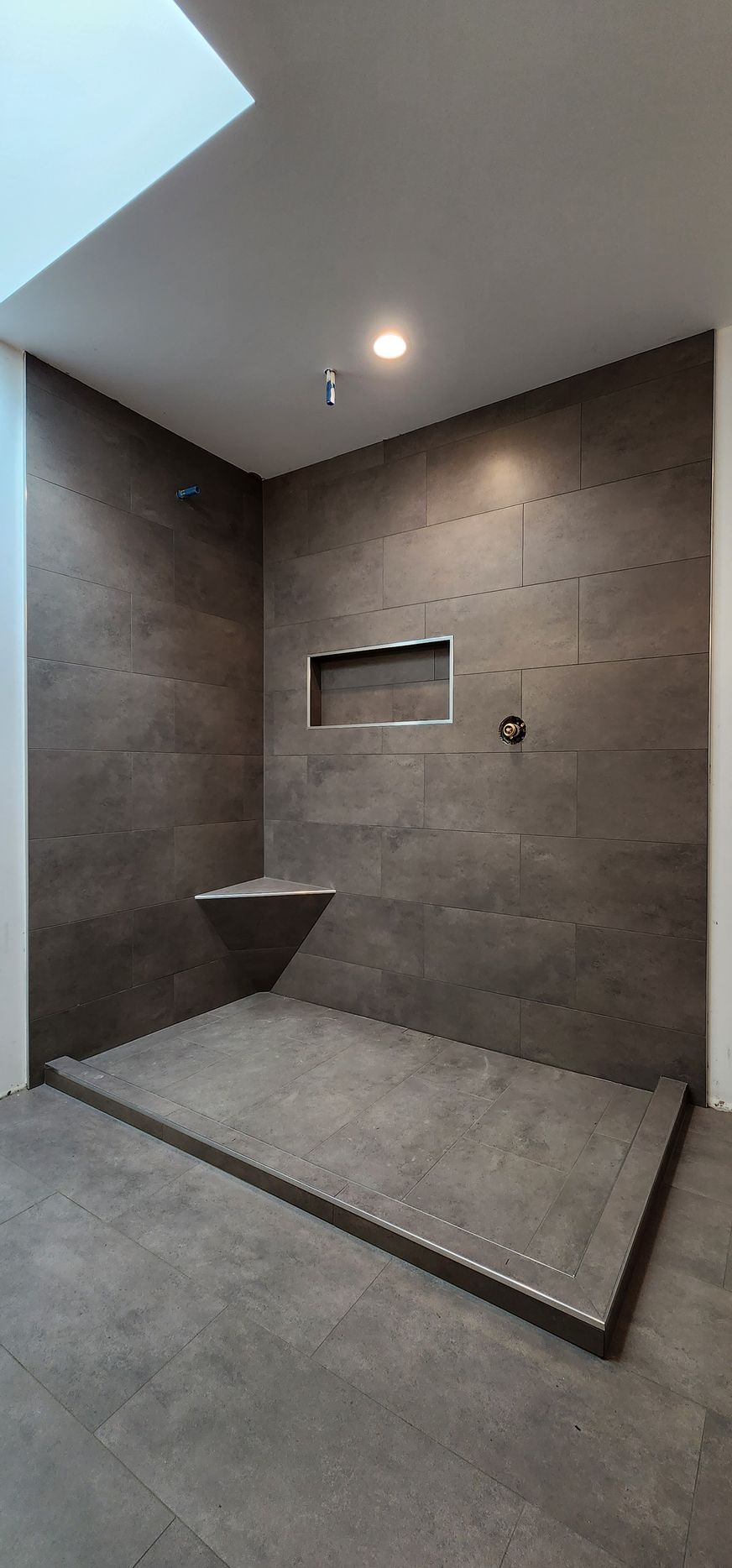 A bathroom with a walk in shower and a bench.