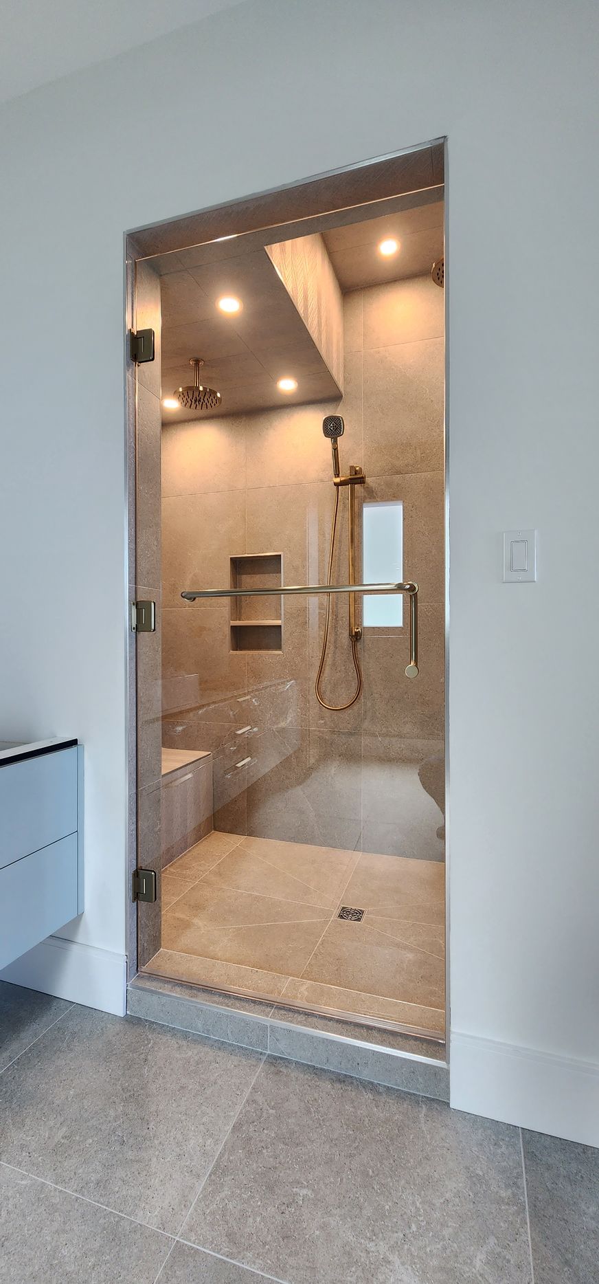 A bathroom with a walk in shower and a glass door.