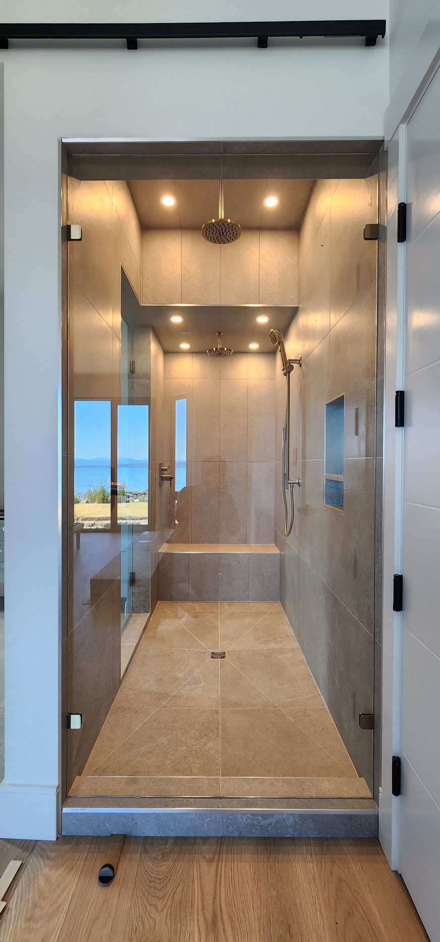 A bathroom with a walk in shower and a glass door.