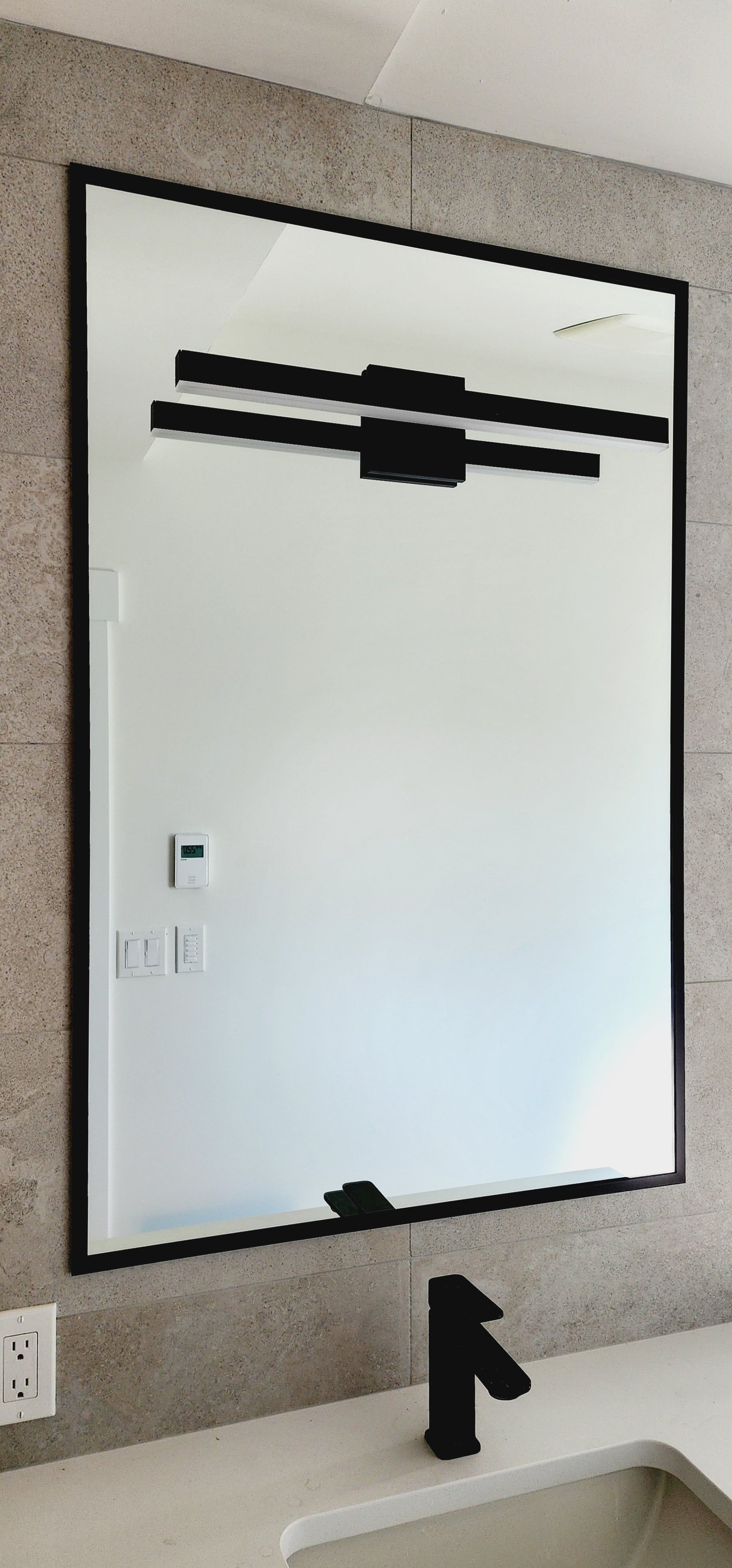 A bathroom mirror is hanging on a wall above a sink.