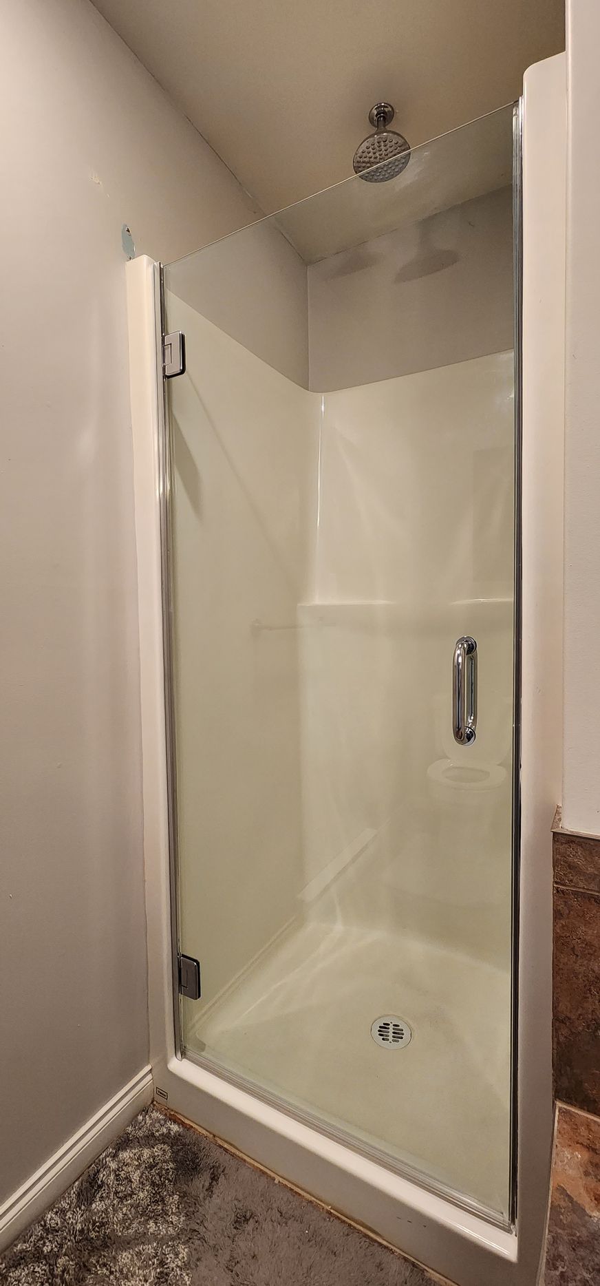 A bathroom with a walk in shower with a glass door.