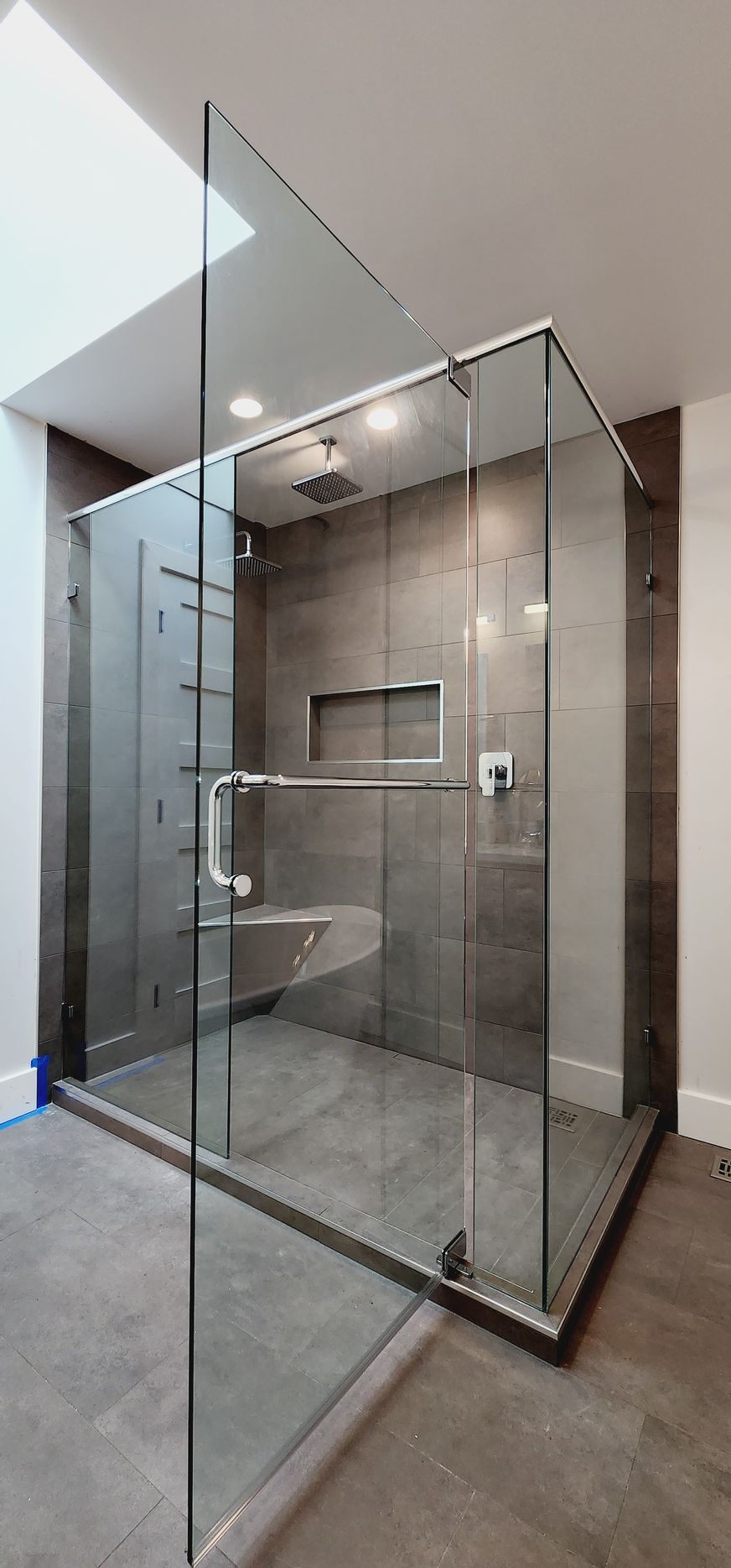 A bathroom with a walk in shower with a glass door.