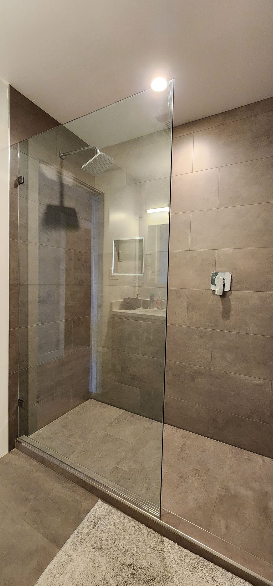 A bathroom with a walk in shower and a sink.