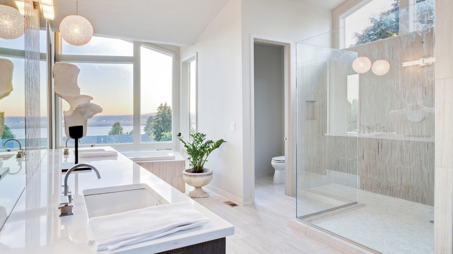 A bathroom with two sinks , a walk in shower and a large window.