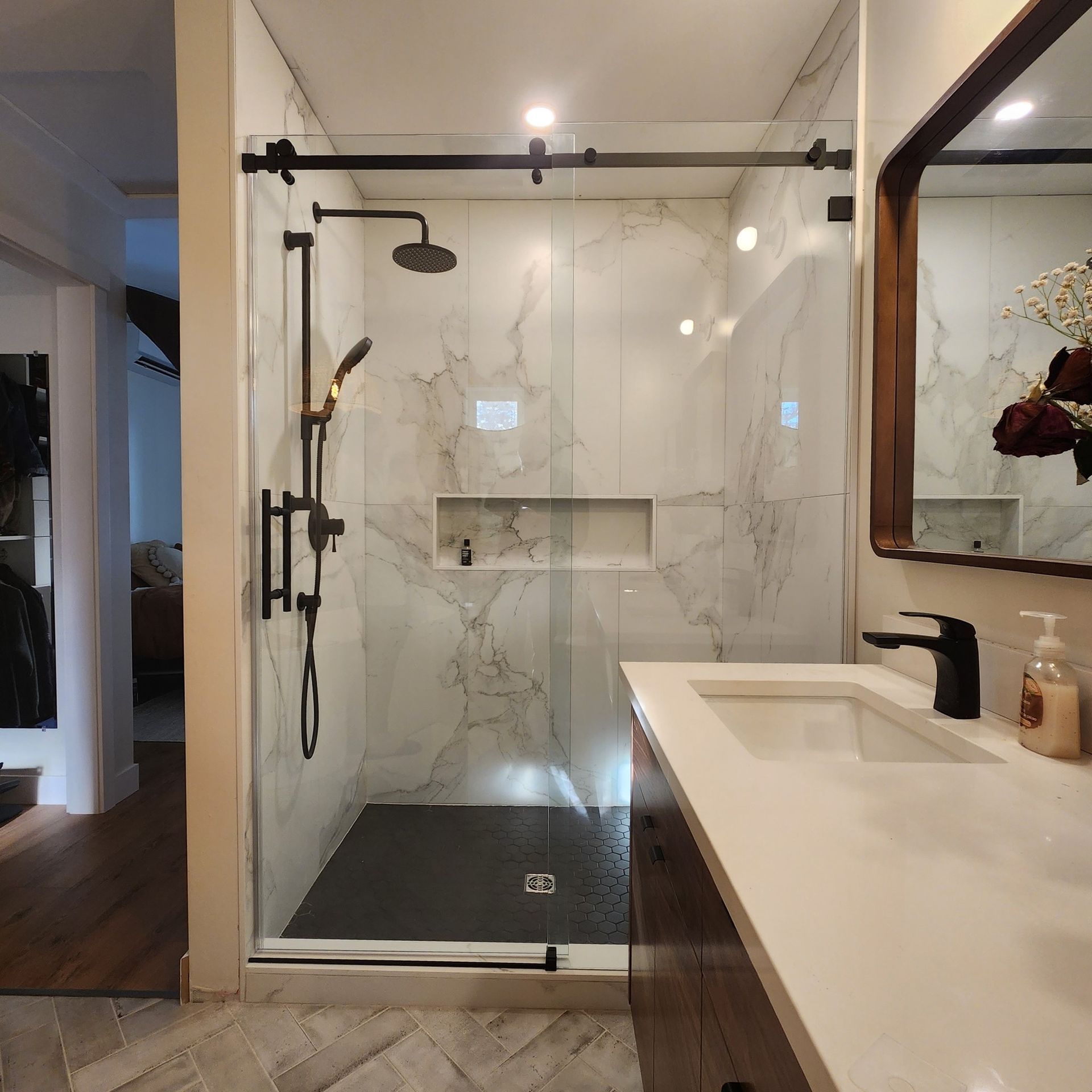 A bathroom with a sink , shower , and mirror.
