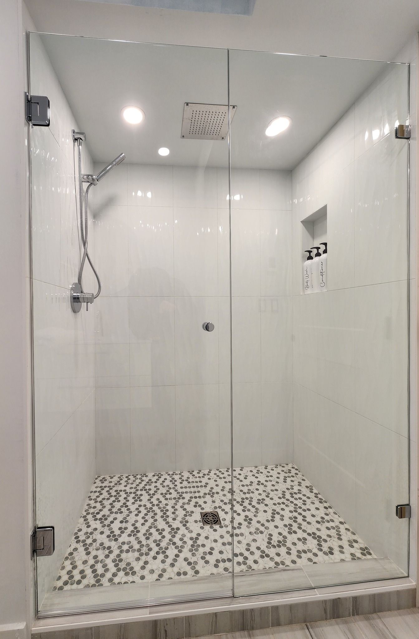 A bathroom with a walk in shower with a glass door and a shower head.