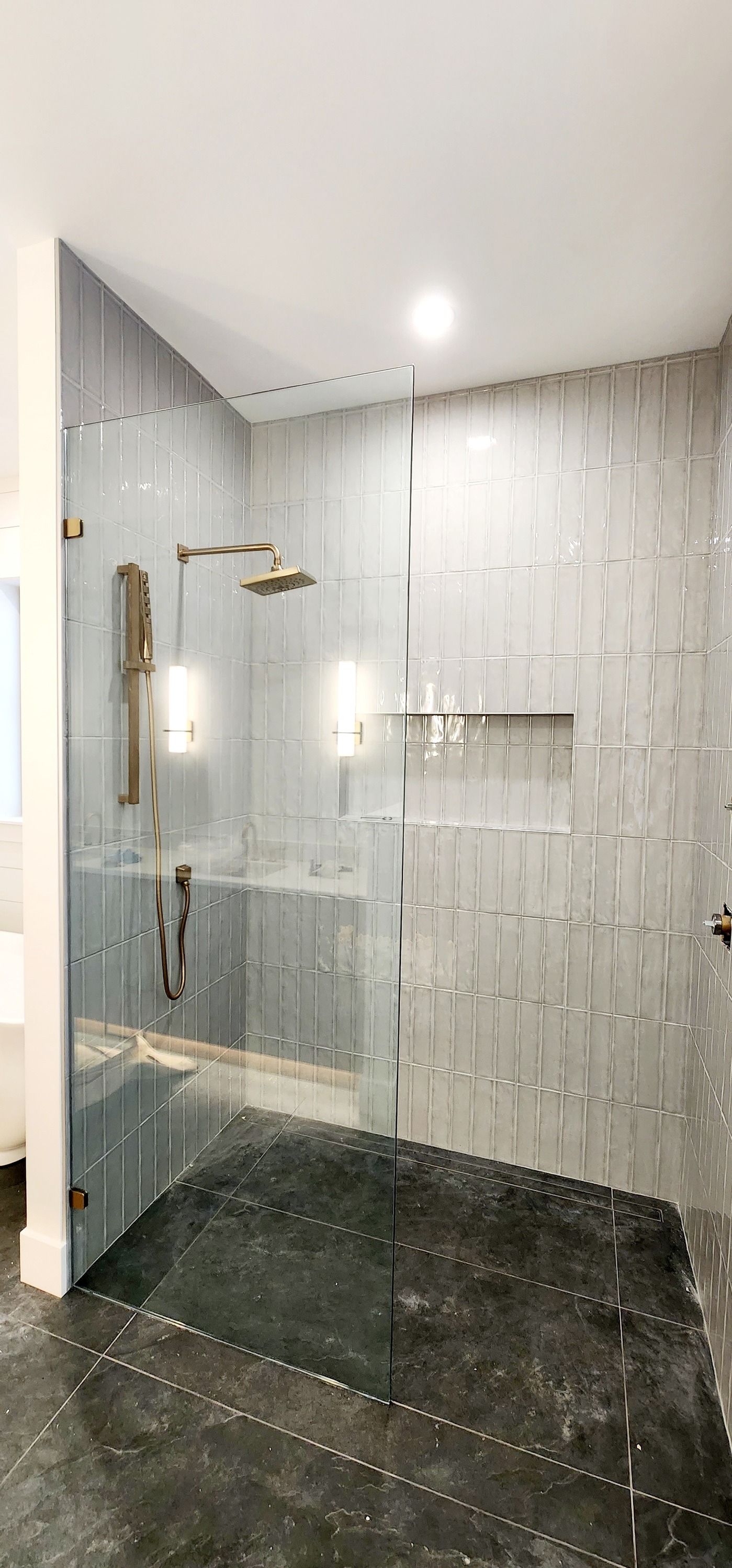 A bathroom with a walk in shower with a glass door.