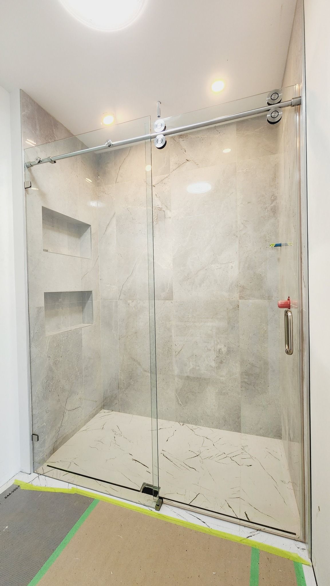 A shower stall with a sliding glass door in a bathroom.