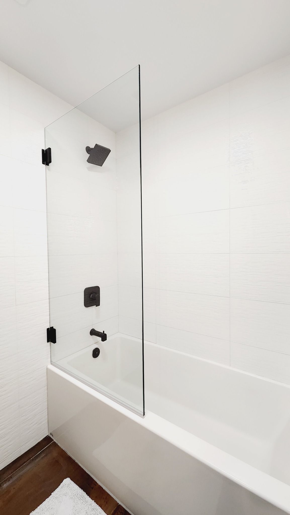 A bathroom with a bathtub and a glass shower door.