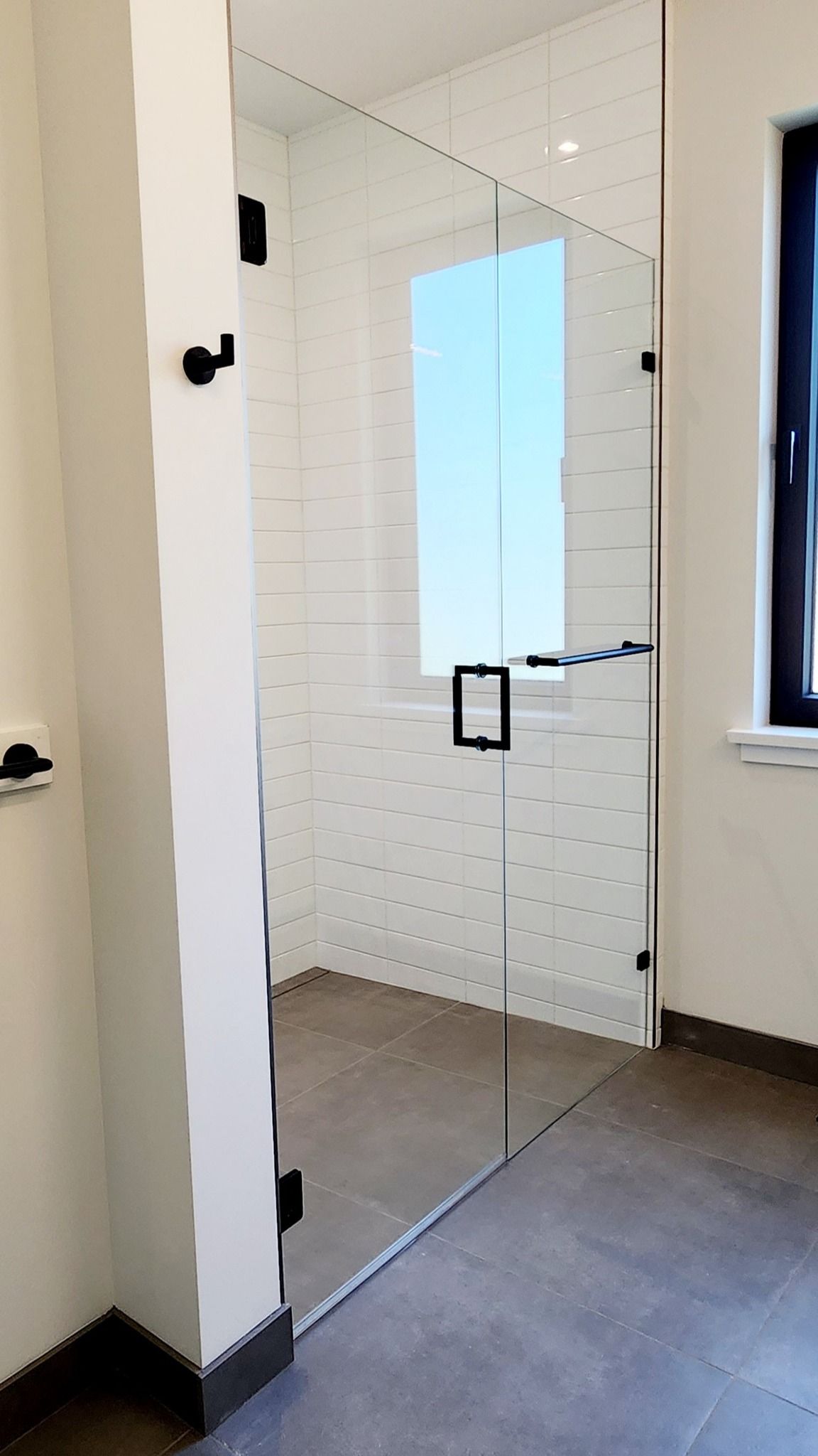 A bathroom with a glass shower door and a window.