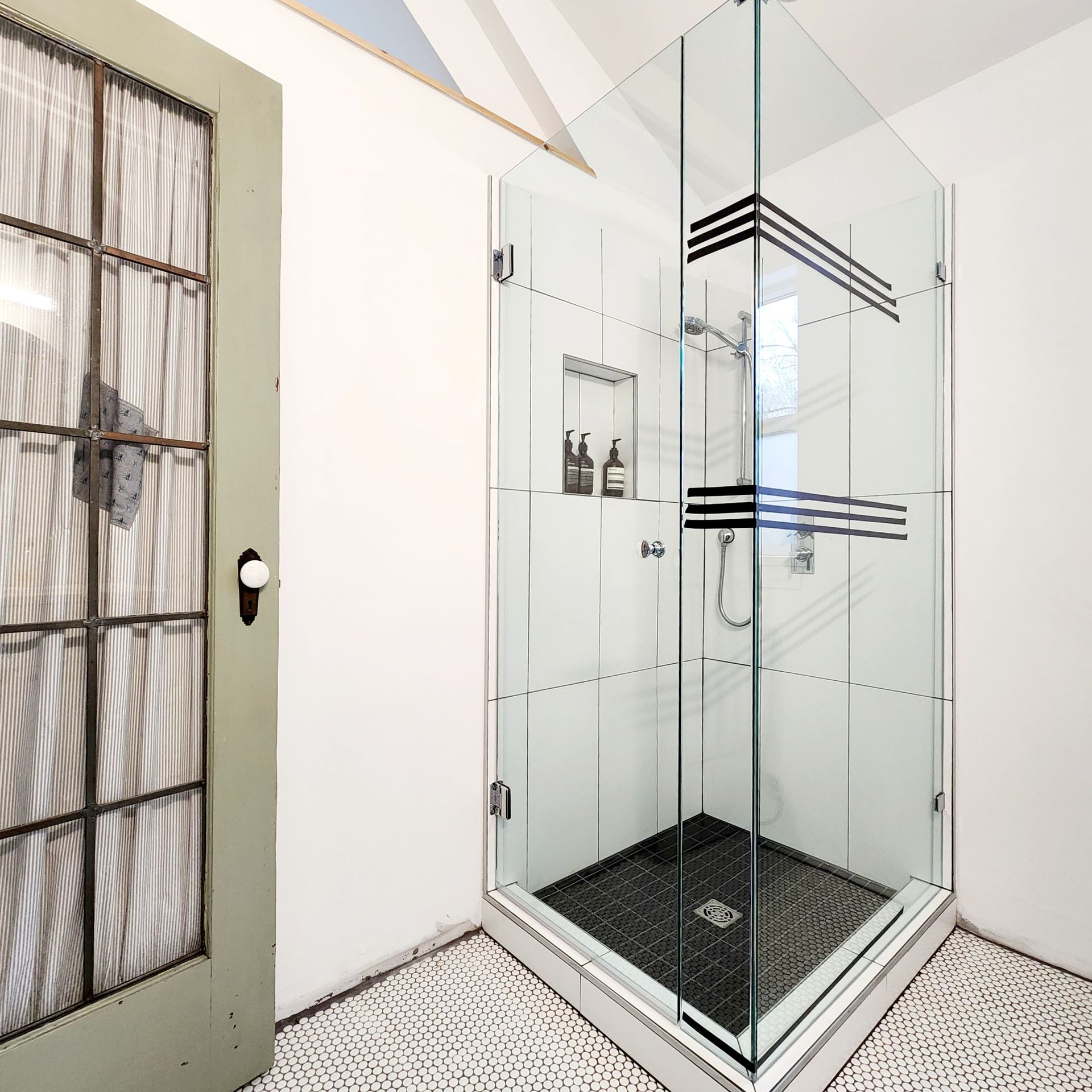A bathroom with a walk in shower with a glass door
