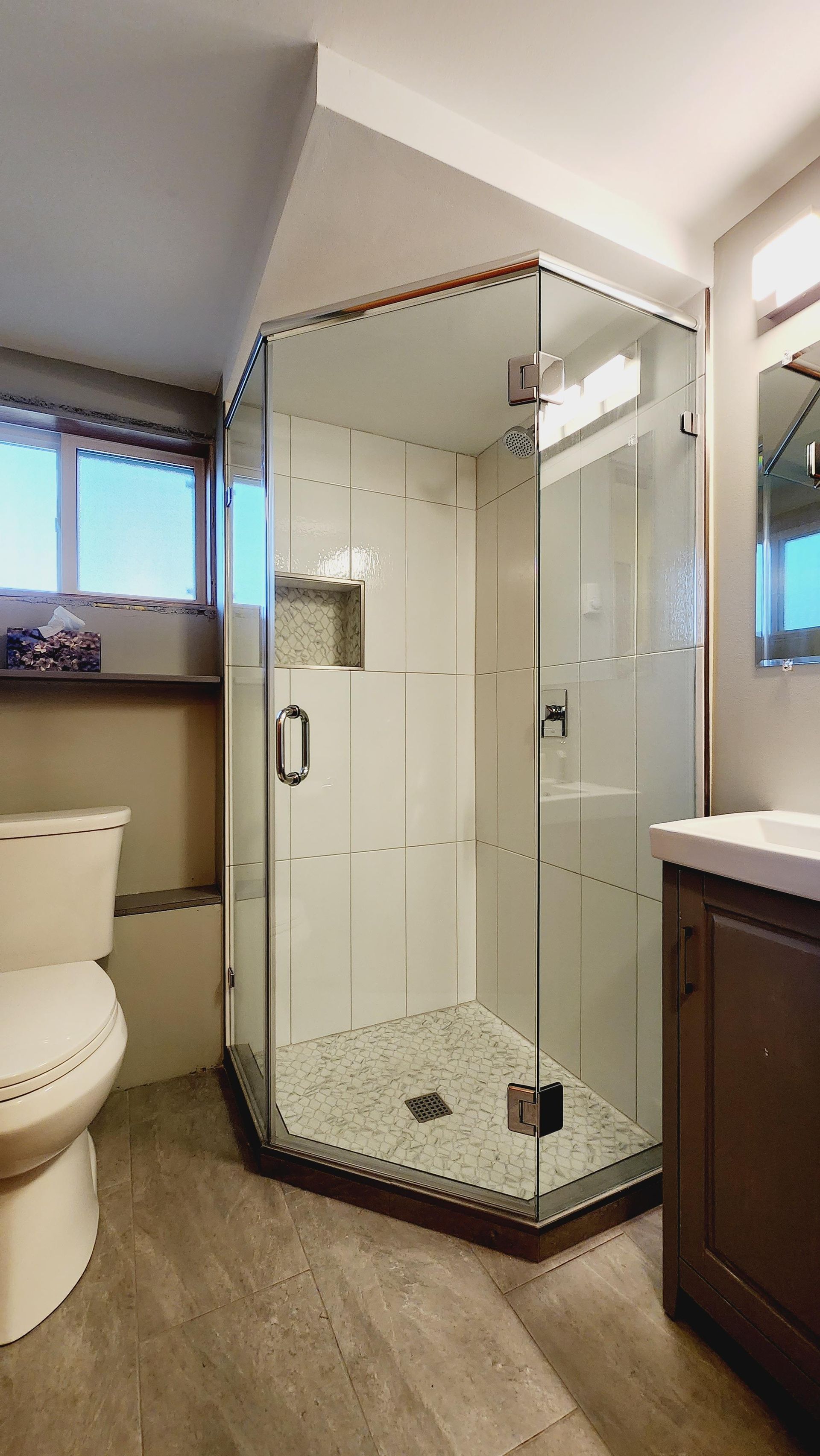 A bathroom with a toilet , sink and walk in shower.