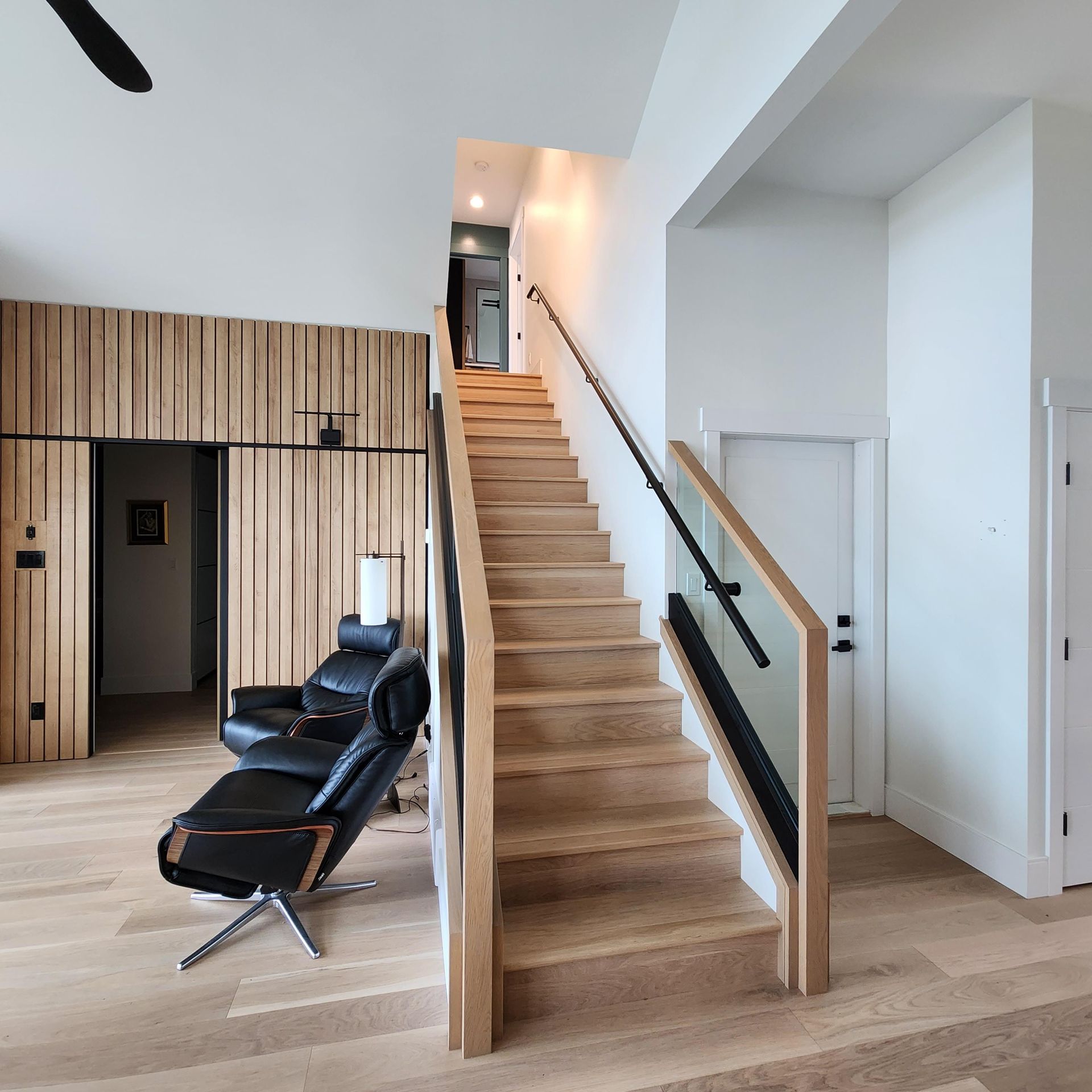 A wooden staircase with a glass railing in a living room